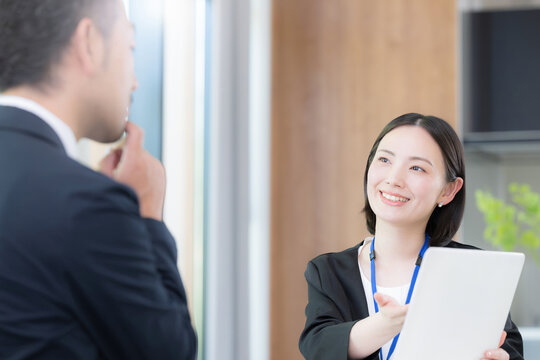 綺麗なオフィスで法人営業でヒアリングしながら提案(プレゼン)する若い女性社員のポートレート信頼と商談　保険や企画の提案などのイメージ