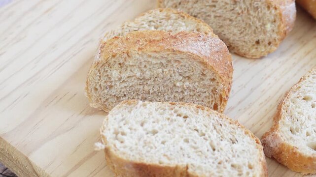 Zoom in on fresh bread slices resting on a wooden board. Ideal for content about food, lifestyle, or baking.