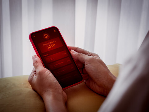 Person checking low balance, empty bank account on mobile banking app with red alert screen. Financial crisis, money shortage, personal finance problem, economic stress and digital payment risk.