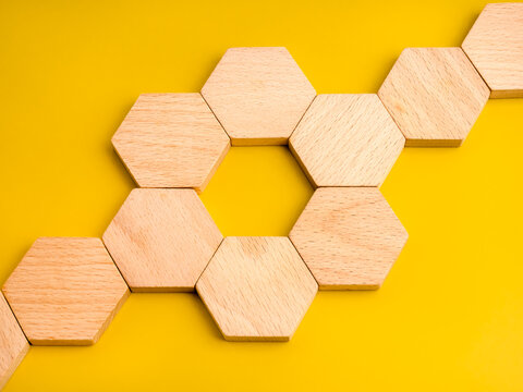 Wooden hexagon blocks forming connected structure on yellow background. System framework, business process, organization, workflow, connection, modular design and strategic planning concept.