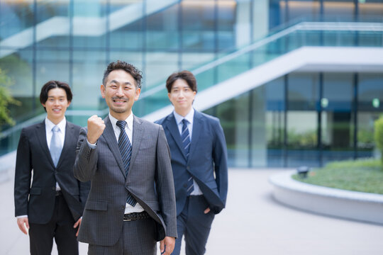 ビジネスチームを率いる40代のリーダーや管理職、社長や経営者、コンサルタントなどの3人複数のビジネスシーンカメラ目線笑顔　ガッツポーズで転職や組織ビルディングや成功のイメージ