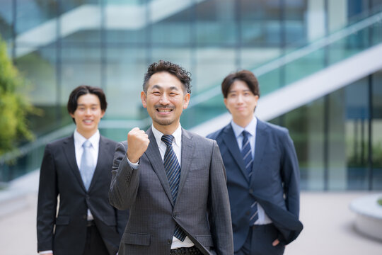 ビジネスチームを率いる40代のリーダーや管理職、社長や経営者、コンサルタントなどの3人複数のビジネスシーンカメラ目線笑顔　ガッツポーズで転職や組織ビルディングや成功のイメージ