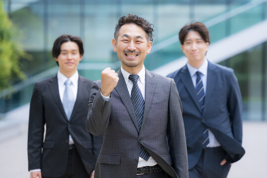 ビジネスチームを率いる40代のリーダーや管理職、社長や経営者、コンサルタントなどの3人複数のビジネスシーンカメラ目線笑顔　ガッツポーズで転職や組織ビルディングや成功のイメージ