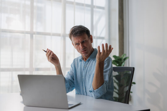 Mature man feeling confused while working with laptop