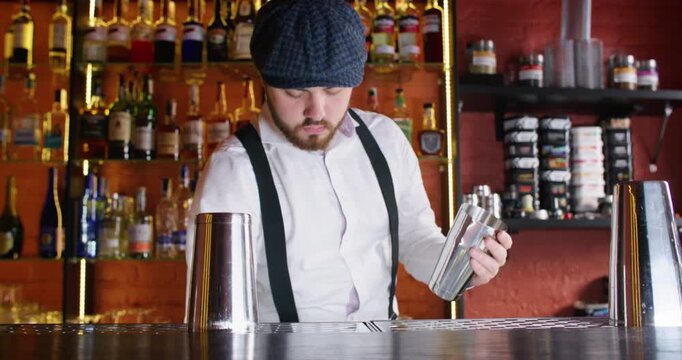 Shaker flair. Skillful barman. Experienced bearded male bartender juggling scooping ice cubes making cocktail at bar counter in pub.
