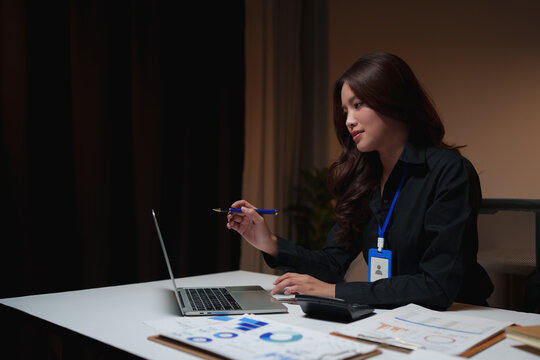 Young businesswoman working late analyzing data on laptop