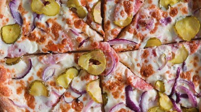Pizza slices with toppings of pickles, onions, and cheese are arranged in a circular pattern on a flat surface. The crisp crust and vibrant colors showcase a creative approach to pizza toppings