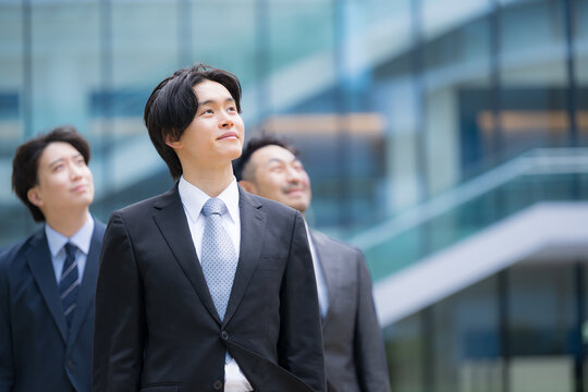 笑顔で歩くスーツで新卒採用や新人の若手ビジネスチームのポジティブ(前向き)な未来を見つめる(見上げる)リクルートイメージ　転職や就活、採用などの笑顔複数の横並び