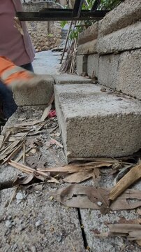 Gloved Hand Cleaning Debris from Concrete Block
