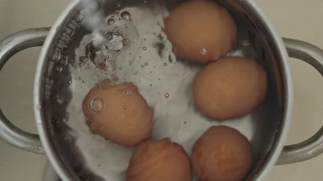 Water pours into a pot with brown eggs creating bubbles