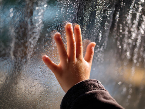 Hand condensation window glass child finger moisture wet touching drawing blurred closeup indoor reflection texture translucent morning cold rain surface skin small arm sleeve curiosity playful