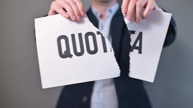 An individual is engaged in an activity where they tear a paper marked with the word quota in a professional setting