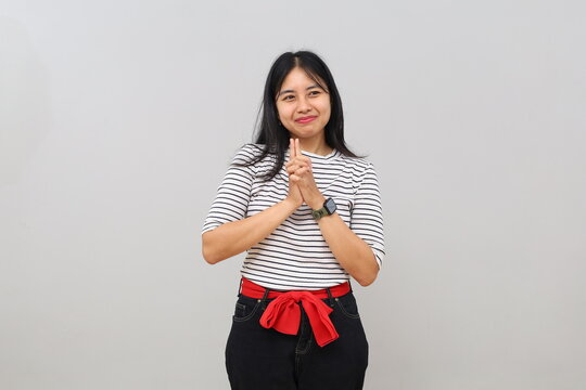 A young woman is planning something, a cunning and mischievous thought, glancing sideways into the empty space with a smile, standing isolated on a white background.