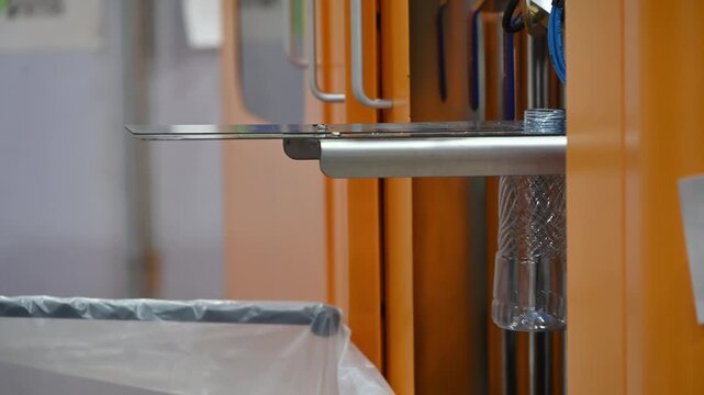 Video of empty plastic PET bottles coming out of blow molding machine onto an automated conveyor belt.