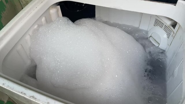 White soap suds swirling inside a washing machine during laundry