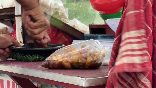 Indonesian Street Food Vendor Grinding Spices for Rujak Sauce