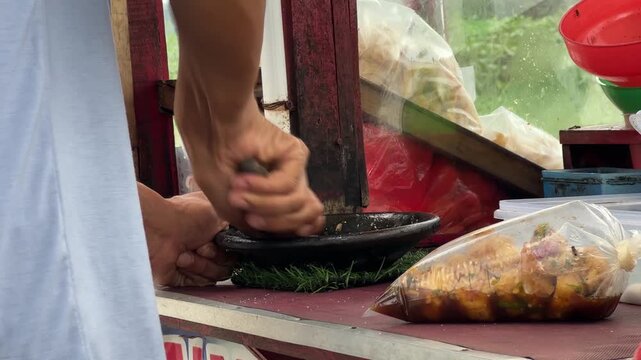 Street Food Vendor Grinding Spices in Traditional Stone Mortar