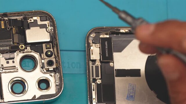Professional mobile phone repair technician working on disassembled smartphone closeup
