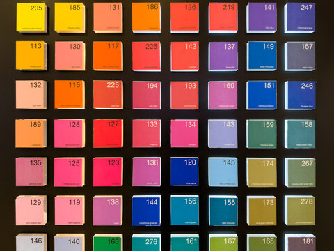 Color swatch display with neatly arranged square tiles showing various shades, each labeled with its name and number on a black background.