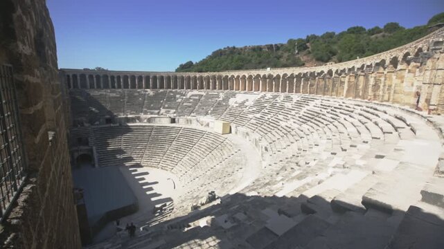 Partially restored classical Roman theater in ancient settlement of Aspendos in Antalya province of Turkey. View of stone seats of semicircle auditorium descending towards stage