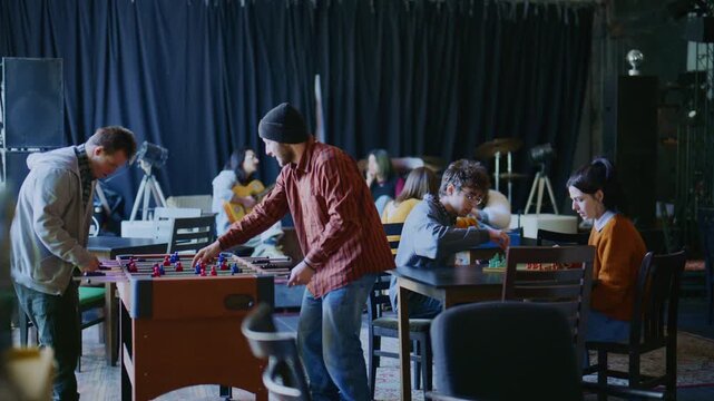 A group of young students relax and socialize in a common room, engaging in various leisure activities.