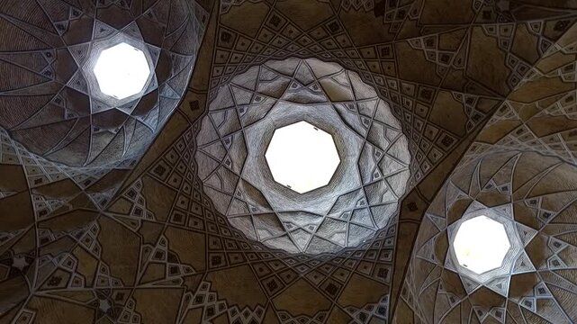  Intricate patterns on the interior of a traditional dome with a bright central skylight. This footage captures the beautiful geometric art and architectural details of a historical mosque. 