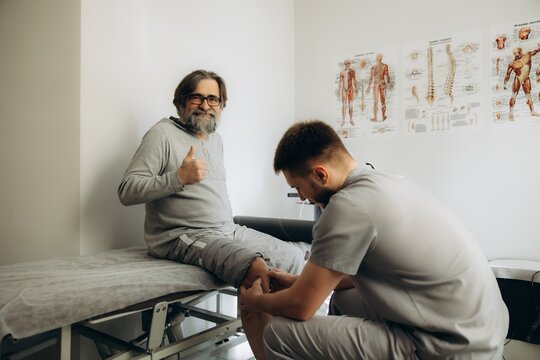 Senior man receiving physical therapy, giving thumbs up