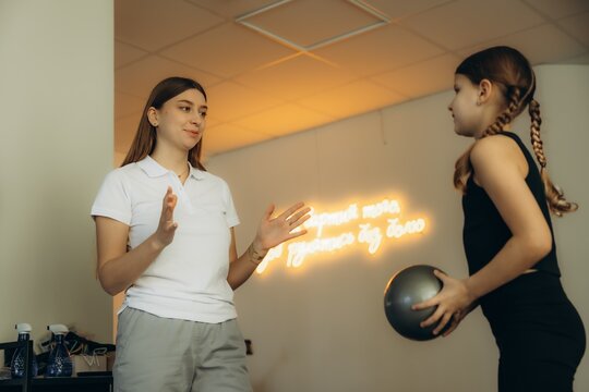 Physiotherapist explaining exercises to little girl with ball