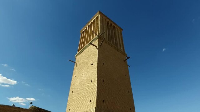  Historical mud brick windcatcher tower standing tall in the desert landscape of Yazd, Iran, symbolizing ancient Persian ventilation technology and sustainable architecture. 