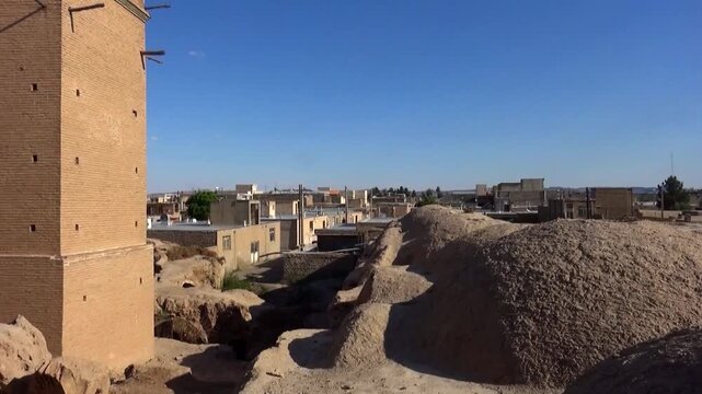  Aerial view of dome shaped adobe roofs and historic windtowers in Yazd, Iran, highlighting ancient desert residential architecture and Persian city culture under a clear blue sky. 