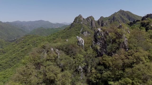 Wild unrestored Great Wall on steep mountain ridge with watchtowers and dramatic landscape, China