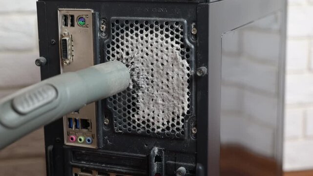 Technician cleaning dust from computer case ventilation grill. Close-up of a service technician using a vacuum cleaner to remove a thick layer of dust from the cooling system ventilation grill