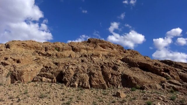  Rocky desert hill under bright daylight and blue sky, revealing layered geology, eroded textures, and natural desert landscape emphasizing morphology and earth tone beauty. 