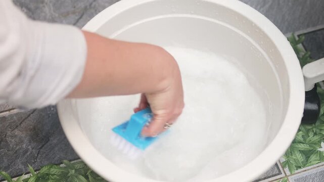 Soapy foam texture in white basin shows rich bubbles for deep cleaning. Brush creates thick lather to effectively treat furniture surfaces. Soapy foam texture indicates high-quality cleaning solution.