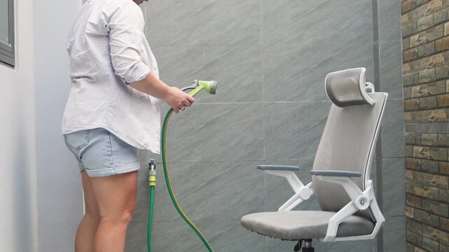 Challenging domestic stereotypes is about independent home care. Woman uses a hose to clean furniture, proving self-reliance. This act of challenging domestic stereotypes redefines roles.