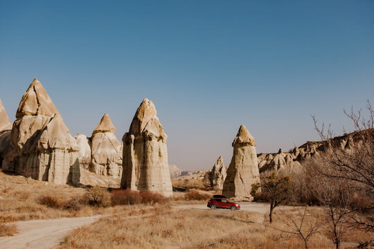Car driving among fairy chimney rock formations in Cappadocia, Turkey