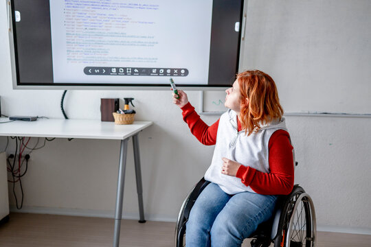 Female student in wheelchair presenting her project in front of classroom.