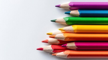 Fototapeta premium A set of colored pencils in various colors is arranged in a straight line on a simple background. The pencils have sharpened tips and are ready for drawing and coloring