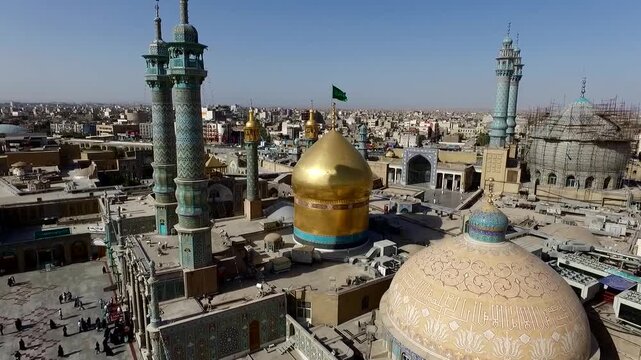  Close aerial composition of a sacred shrine with a brilliant golden dome and patterned blue dome, framed by minarets and dense city blocks, expressing devotion, heritage, and architectural detail. 