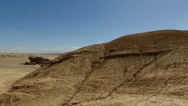  Dome shaped rock hill dominates a desert scene beneath blue sky, highlighting stratified sandstone, natural erosion, and the austere beauty of a remote geological landscape in warm daylight. 