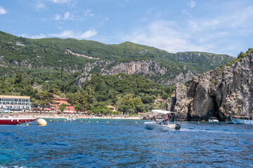 Fototapeta premium Palaiokastritsa sandy beach, Corfu island, Greece. Seaside hotels, lush green hills, turquoise waters