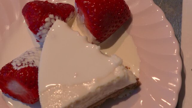 Top down view of fresh cheesecake dessert with strawberries and cream. 4K.