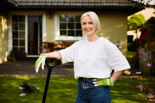 Mature woman with shovel smiling in backyard garden