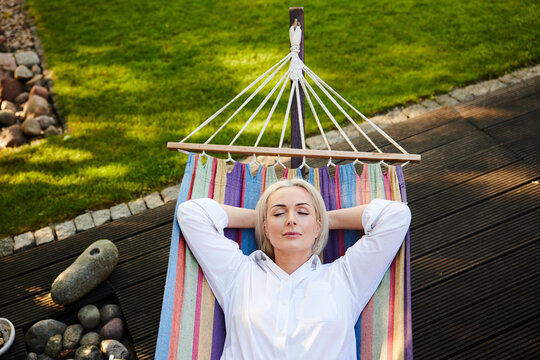 Mature woman napping in colorful hammock on garden deck