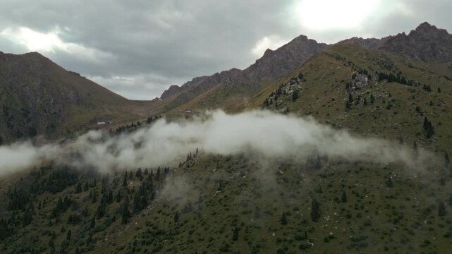 Aerial view of a single white cloud hanging over mountain slopes