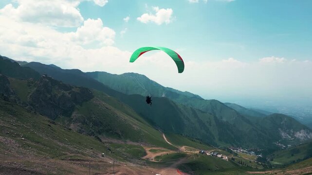 Aerial view of a solo paraglider flying above mountain valley