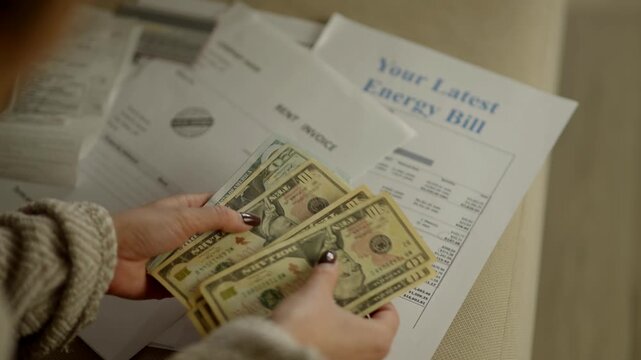 Woman Counting US Dollar Banknotes Over Utility Bills. Home Budget and Energy Expenses. Financial Management and Expenses Accounting