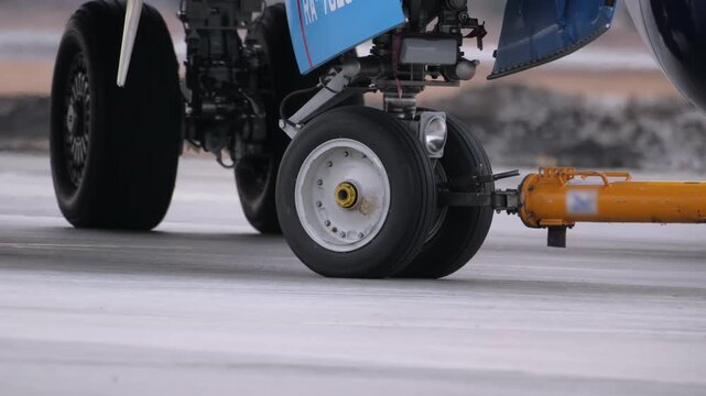 Airplane landing gear runway. Airport terminal maintenance crew aircraft towing vehicle. Close-up of airplane's wheels.