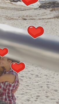Vertical video: Couple embracing beach pan causing hearts drifting across pair and bar sweeping ads