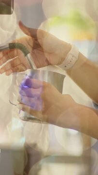 Vertical video: Barista placing pitcher under wand, inserting wand, foaming milk for coffee